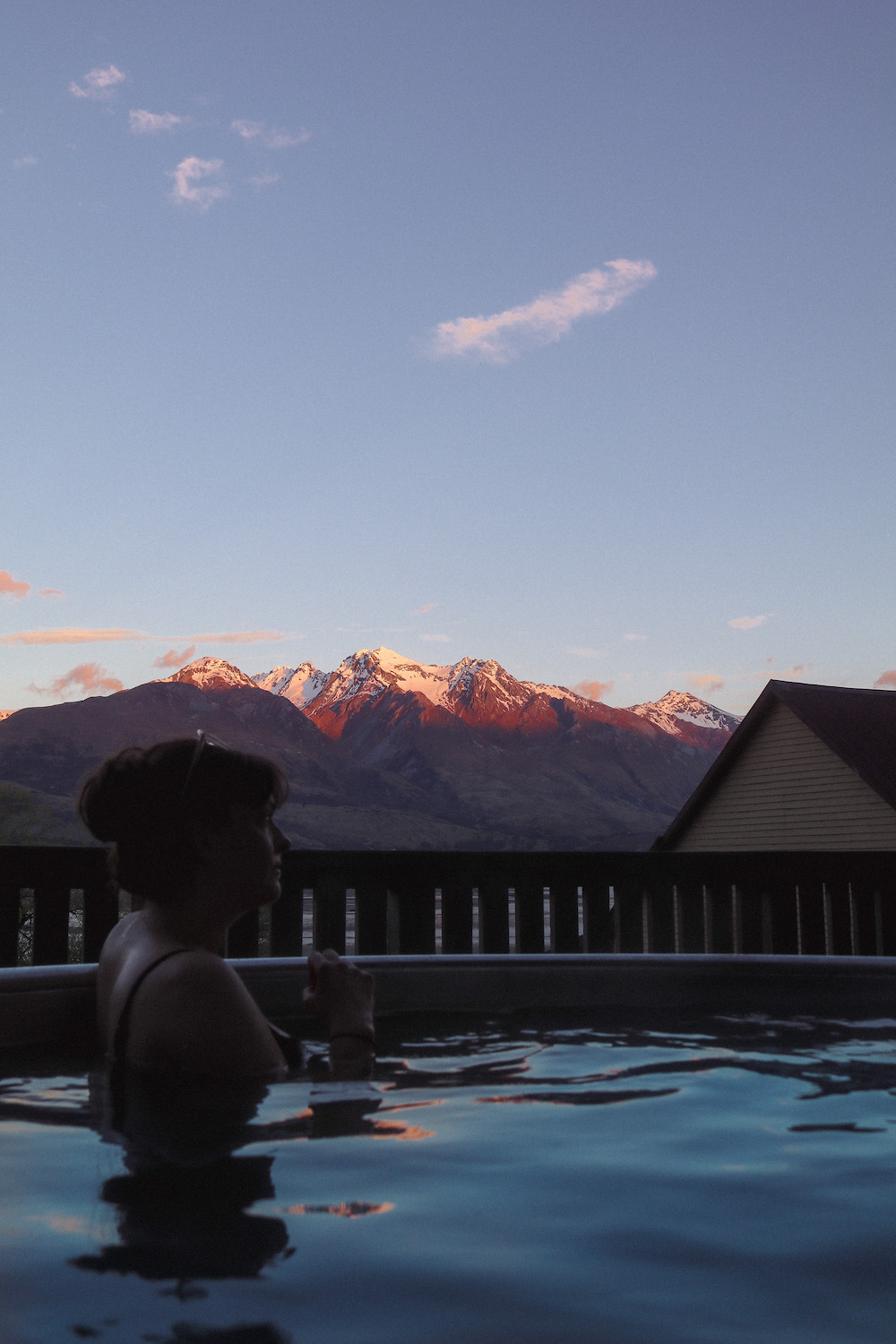 Sitting in a warm hot tub overlooking the pink sky and distant mountains